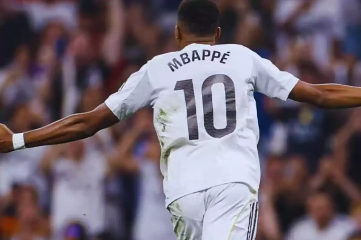 Soccer player celebrating with arms outstretched, wearing a white jersey with the number 10 and the name Mbappé on the back