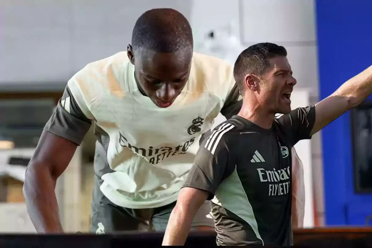 Dos personas con uniforme de entrenamiento del Real Madrid, una de ellas inclinada hacia adelante y la otra levantando el brazo y gritando