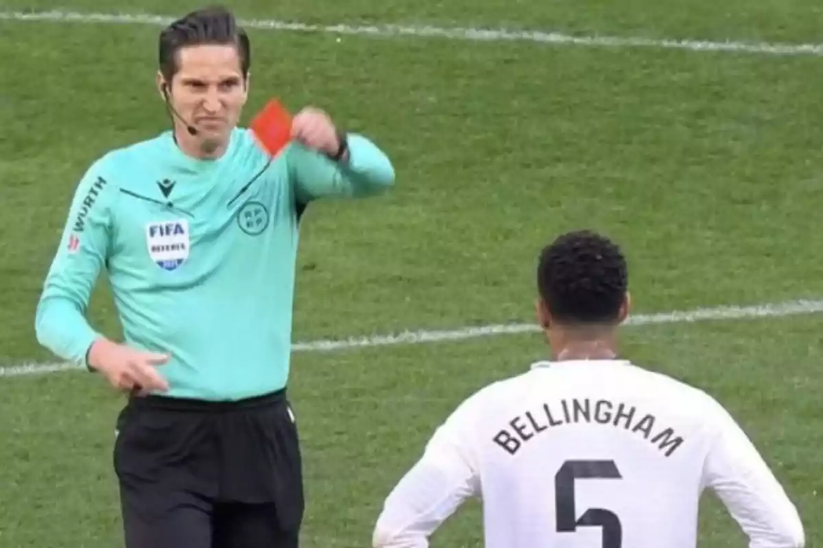 Un árbitro muestra una tarjeta roja a un futbolista con el nombre Bellingham y el número 5 en su camiseta durante un partido de fútbol. Un árbitro muestra una tarjeta roja a un futbolista con el nombre Bellingham y el número 5 en su camiseta durante un partido de fútbol.