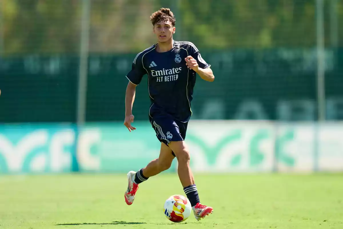 Young player in a dark blue Real Madrid uniform running on a soccer field while controlling the ball Young player in a dark blue Real Madrid uniform running on a soccer field while controlling the ball