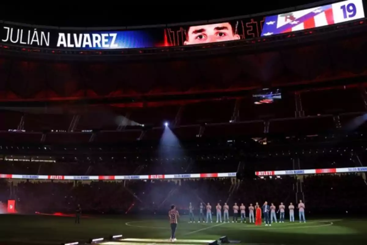 Presentación de un jugador en un estadio de fútbol con su nombre y número en la pantalla gigante mientras el público observa desde las gradas Presentación de un jugador en un estadio de fútbol con su nombre y número en la pantalla gigante mientras el público observa desde las gradas