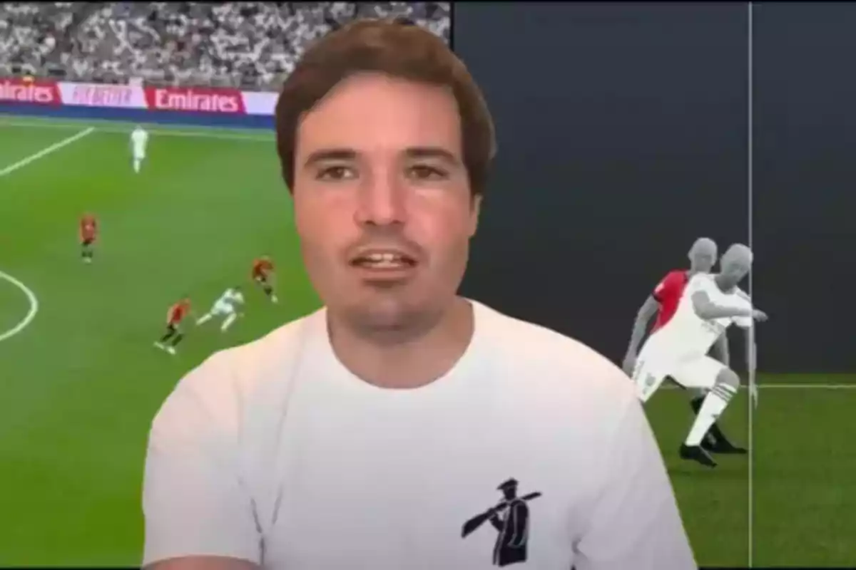 Man in a white jersey speaking in front of a screen displaying a soccer play and a graphic analysis of the match
