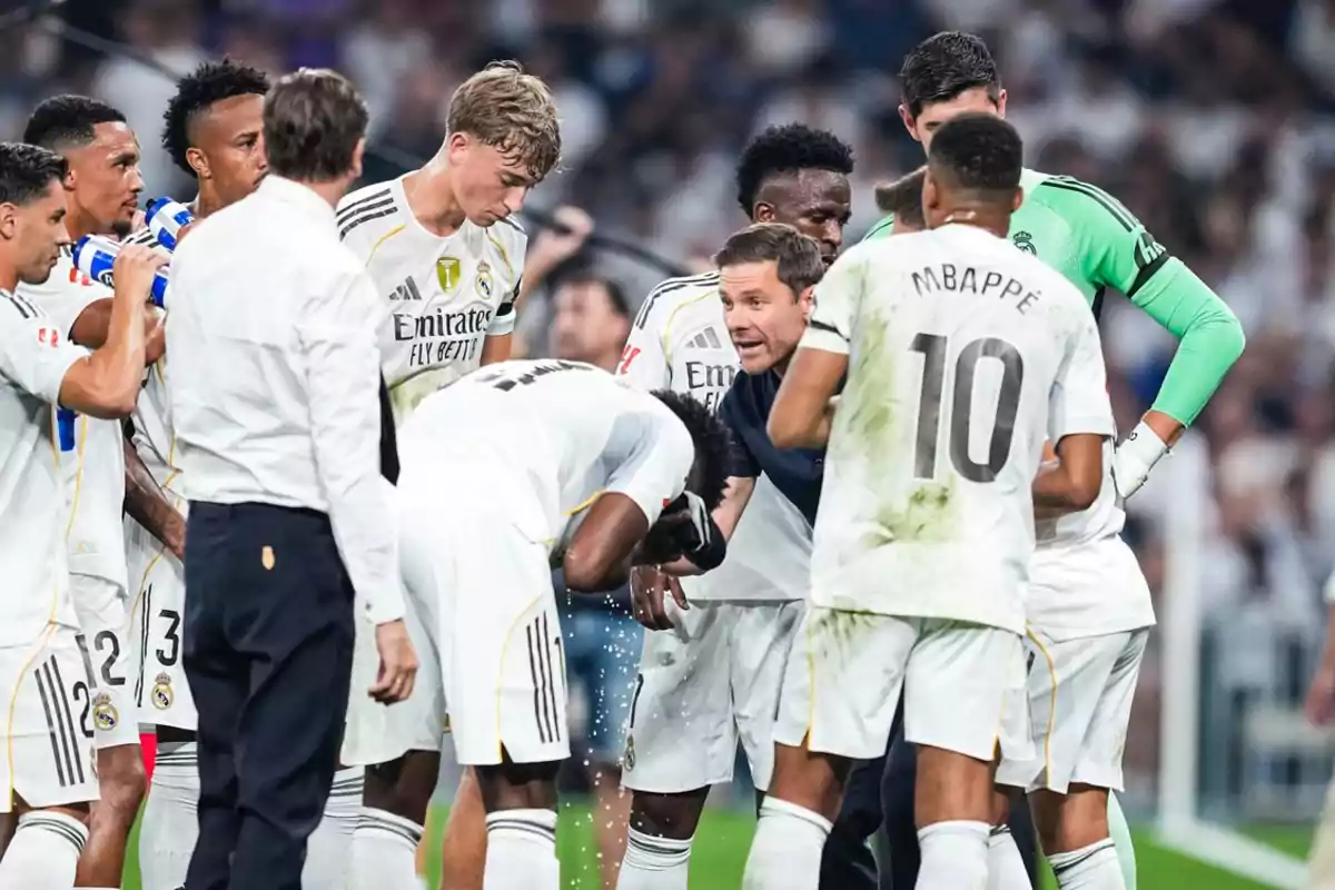 Real Madrid players gathered in a circle with their coach during a break in the match, some drinking water and one cooling his head while they listen to instructions. Real Madrid players gathered in a circle with their coach during a break in the match, some drinking water and one cooling his head while they listen to instructions.