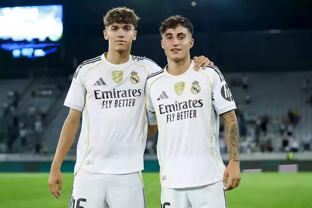 Two young players in Real Madrid’s white uniform pose together in a stadium.