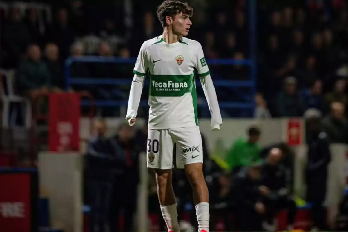 Soccer player in a white and green uniform on the field during a match Soccer player in a white and green uniform on the field during a match