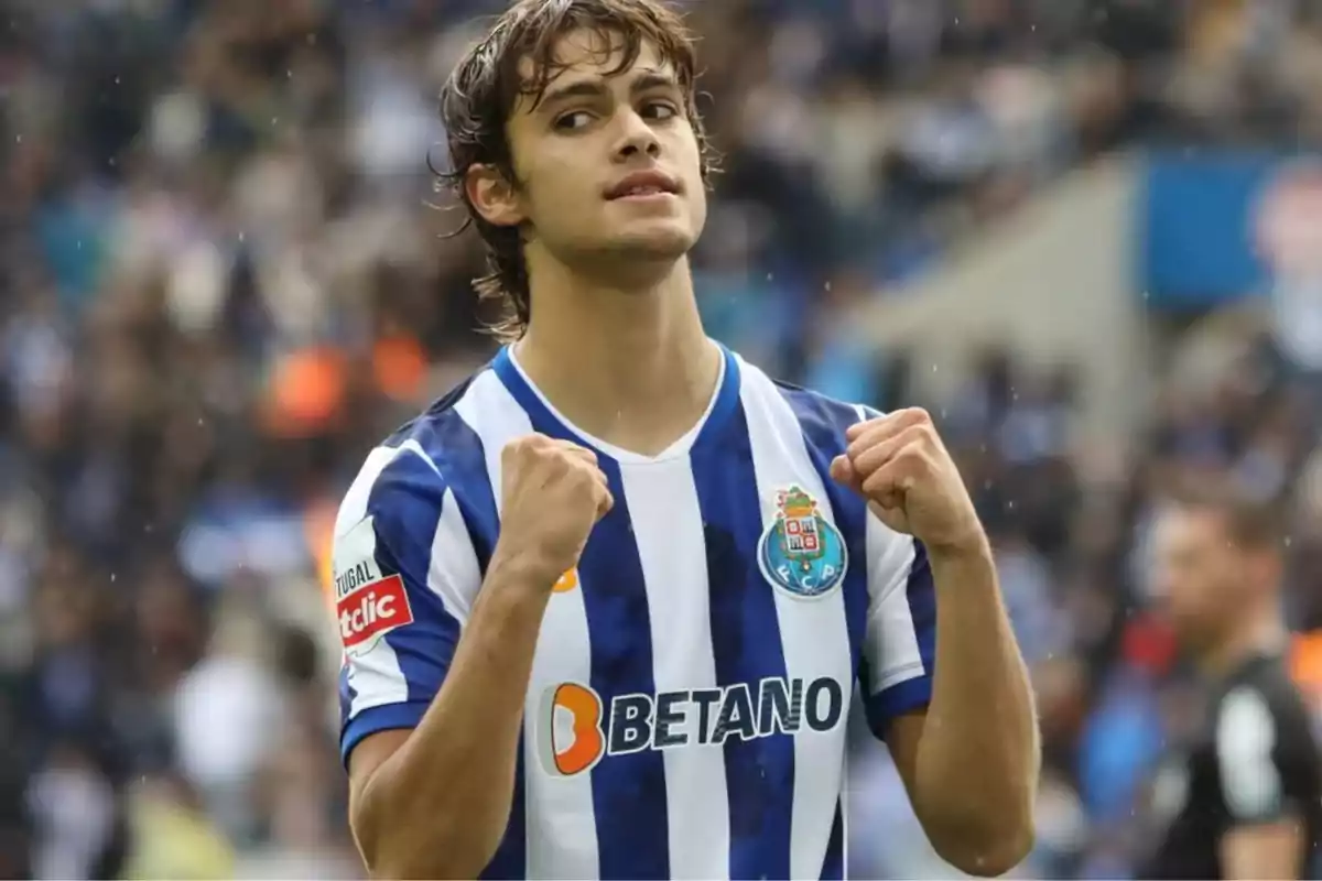 Soccer player in a blue and white uniform celebrating in a stadium full of fans Soccer player in a blue and white uniform celebrating in a stadium full of fans