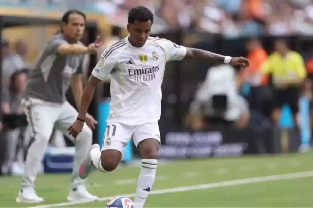 Real Madrid player about to kick the ball during a match with a coach giving instructions in the background Real Madrid player about to kick the ball during a match with a coach giving instructions in the background