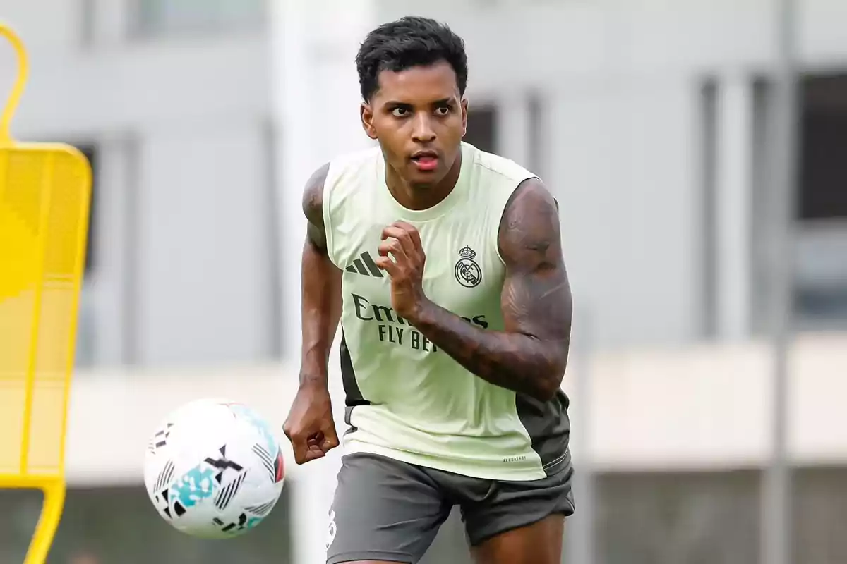 Real Madrid player training in a sleeveless jersey with a ball nearby on the training field