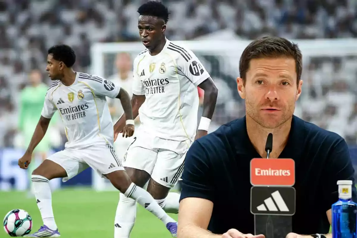 Un entrenador de fútbol da una conferencia de prensa mientras dos jugadores del Real Madrid juegan en el campo al fondo