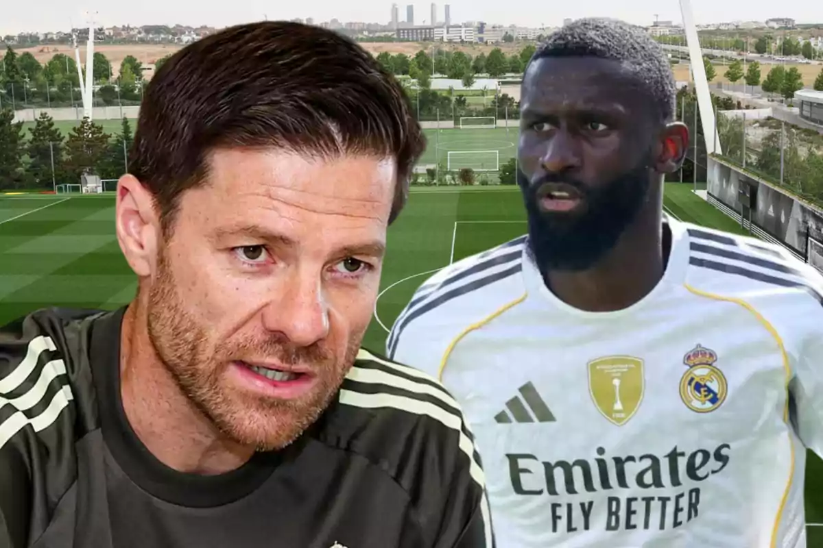 Dos personas con ropa del Real Madrid en primer plano sobre un campo de entrenamiento de fútbol