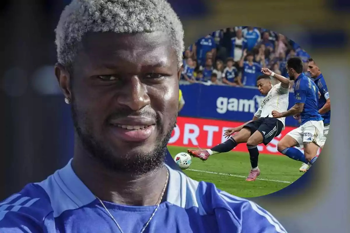Un futbolista con cabello rubio y barba viste un uniforme azul mientras al fondo se muestra una escena de un partido de fútbol con jugadores en acción dentro del campo.