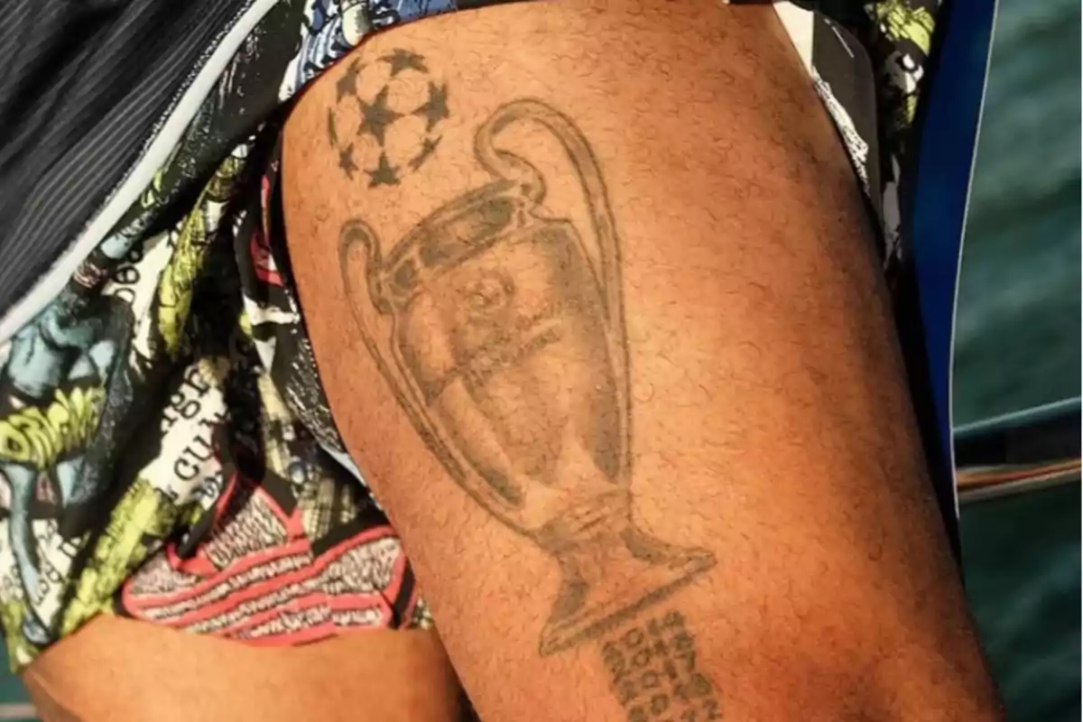 Tatuaje de la copa de la Champions League en el muslo de una persona con fechas grabadas debajo Tatuaje de la copa de la Champions League en el muslo de una persona con fechas grabadas debajo