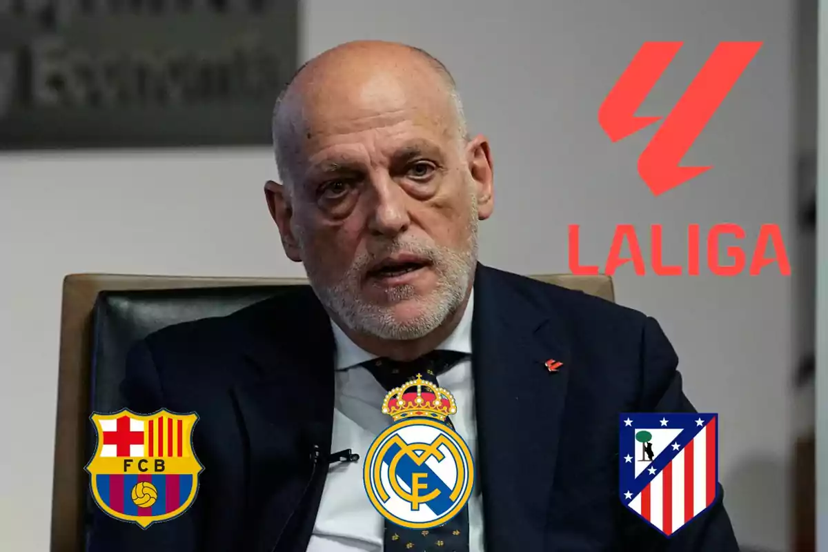 Bald man in a dark suit sitting in front of a background with the LaLiga logo and the crests of Barcelona, Real Madrid, and Atlético de Madrid.
