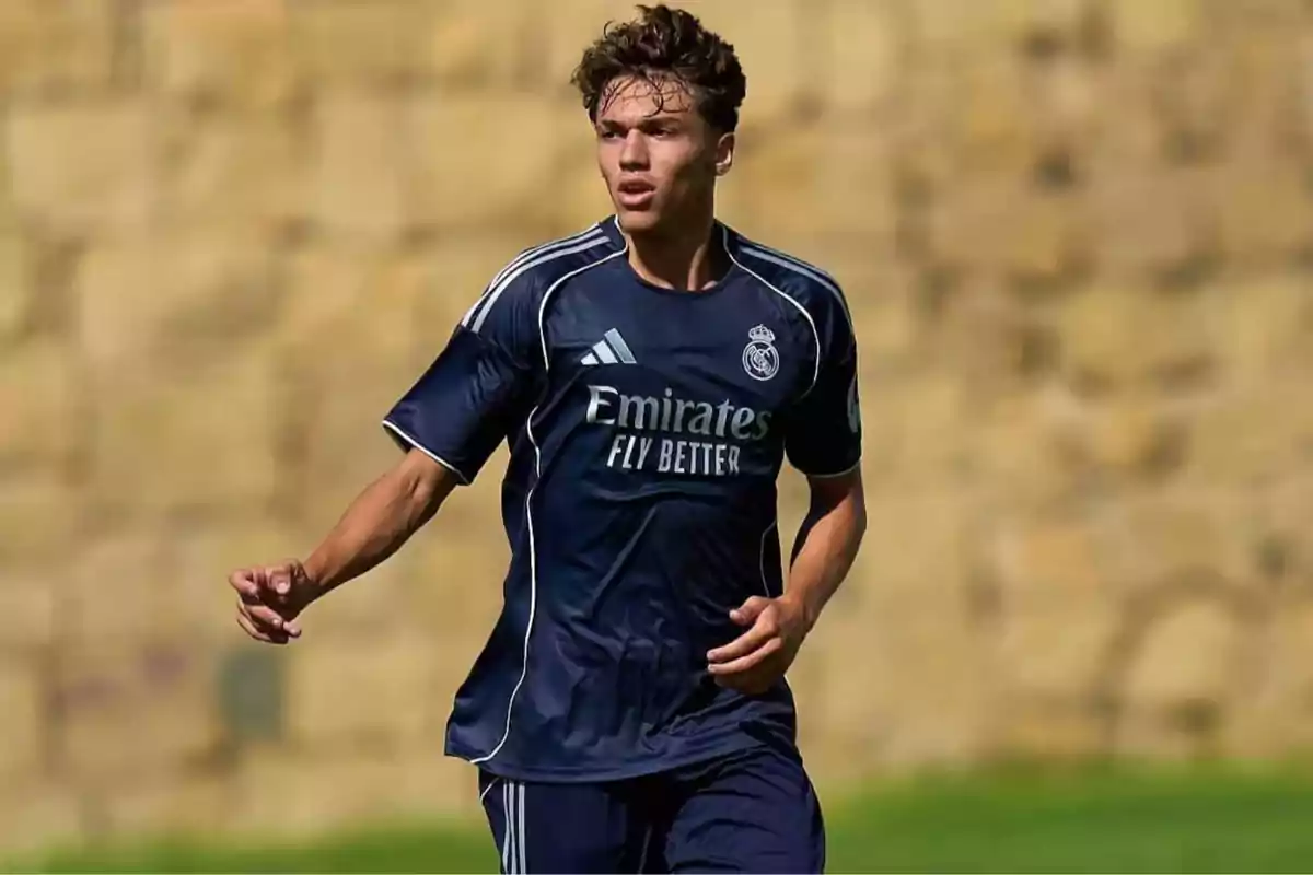 Joven futbolista con uniforme azul marino del Real Madrid en acción durante un partido al aire libre Joven futbolista con uniforme azul marino del Real Madrid en acción durante un partido al aire libre