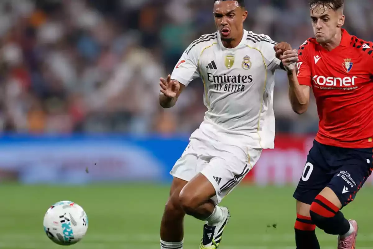 Two players compete for the ball during a match, one wearing a white uniform and the other wearing a red uniform. Two players compete for the ball during a match, one wearing a white uniform and the other wearing a red uniform.