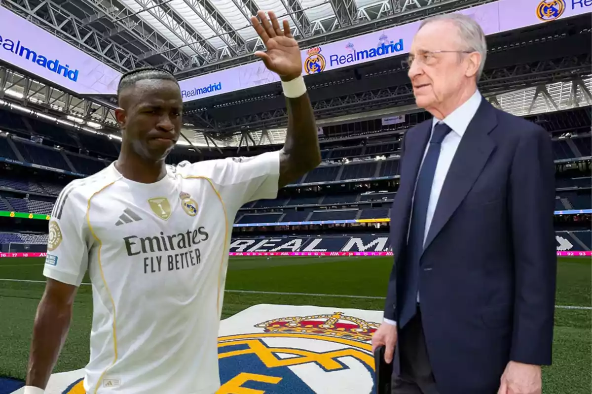 Un futbolista del Real Madrid saluda en el estadio junto a un hombre de traje sobre el césped con el escudo del club.