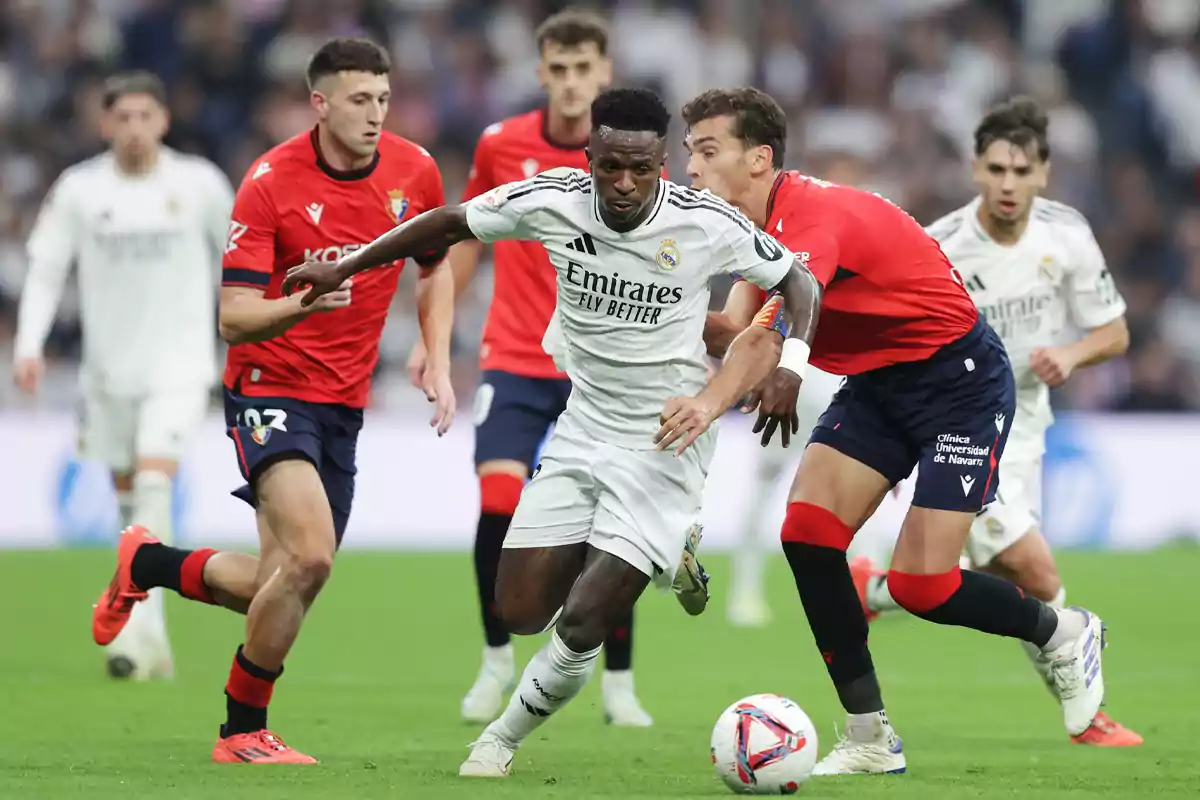 Futbolistas de los equipos Real Madrid y Osasuna disputan el balón durante un partido en el campo Futbolistas de los equipos Real Madrid y Osasuna disputan el balón durante un partido en el campo