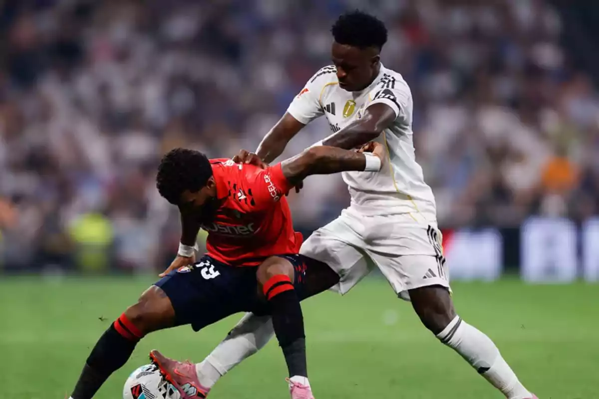 Two players compete for the ball during a match in a stadium full of spectators. Two players compete for the ball during a match in a stadium full of spectators.