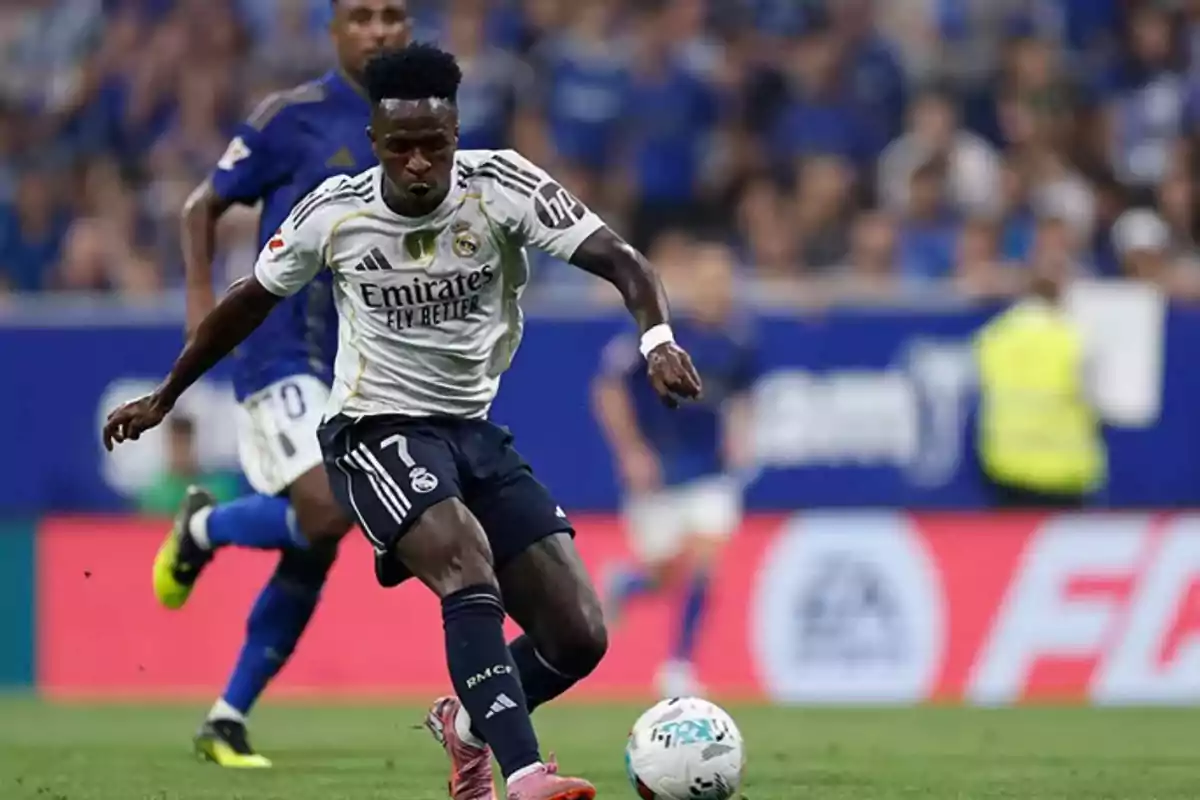 Futbolista del Real Madrid controlando el balón durante un partido con un rival al fondo Futbolista del Real Madrid controlando el balón durante un partido con un rival al fondo