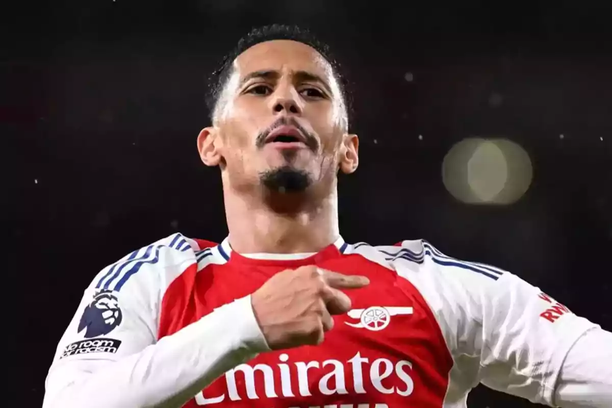 Arsenal footballer celebrating a goal by pointing to the badge on his jersey during a match Arsenal footballer celebrating a goal by pointing to the badge on his jersey during a match