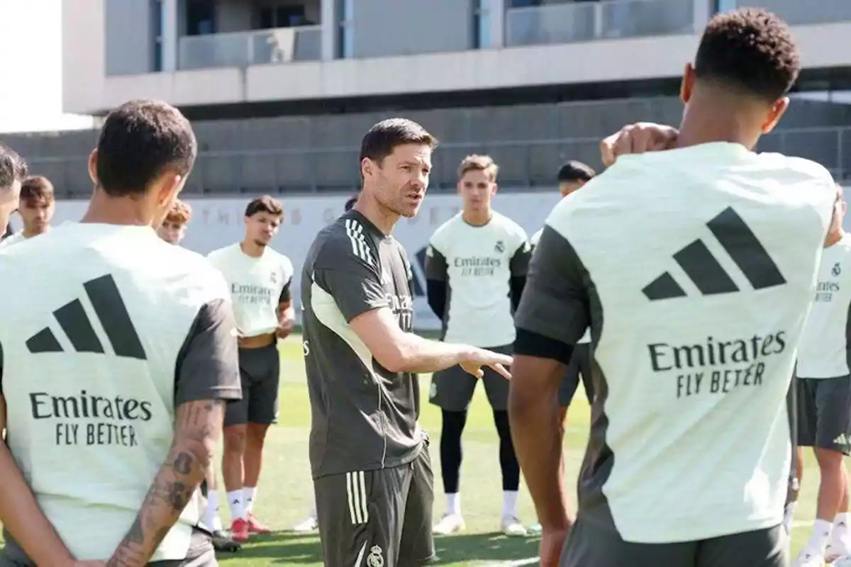Entrenador de fútbol dando indicaciones a un grupo de jugadores durante una práctica en campo al aire libre Entrenador de fútbol dando indicaciones a un grupo de jugadores durante una práctica en campo al aire libre