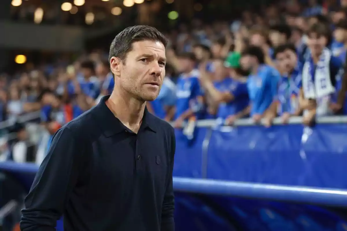 Man in a navy blue jersey standing in front of a crowd in a soccer stadium Man in a navy blue jersey standing in front of a crowd in a soccer stadium