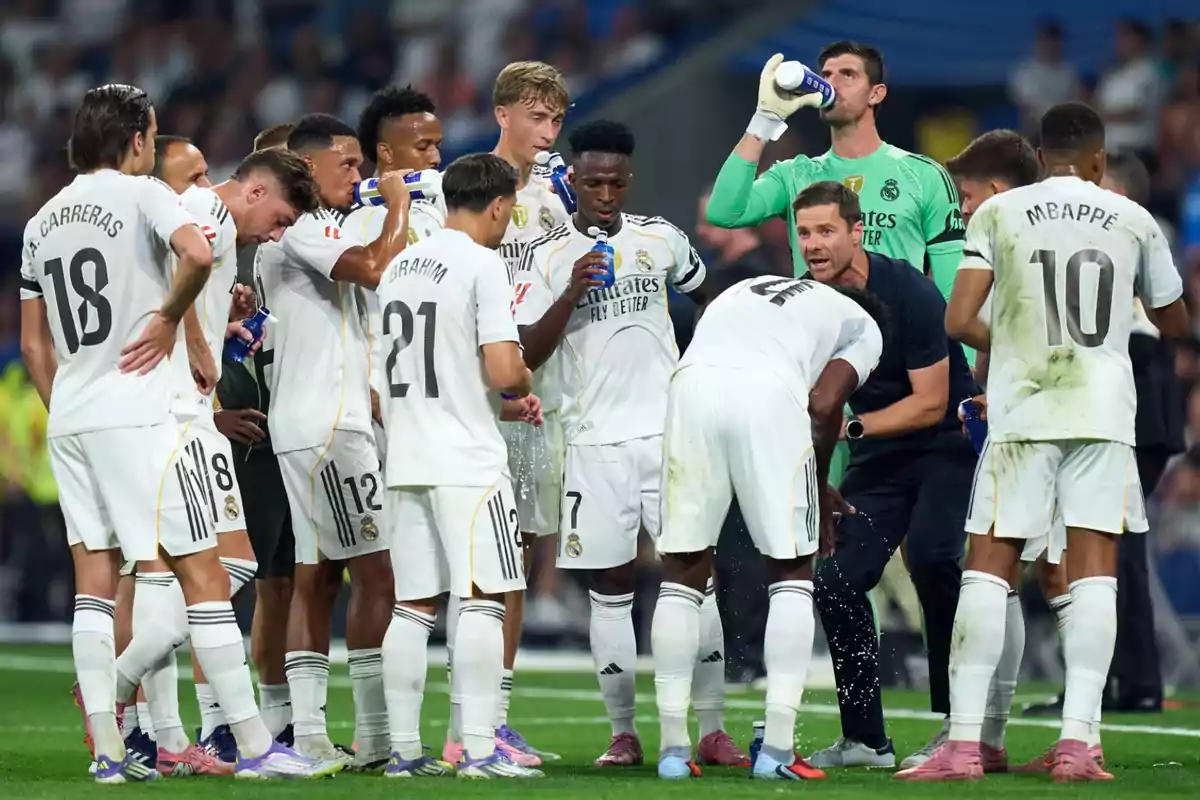 Jugadores de fútbol del Real Madrid reunidos en círculo durante una pausa para hidratarse en un partido Jugadores de fútbol del Real Madrid reunidos en círculo durante una pausa para hidratarse en un partido