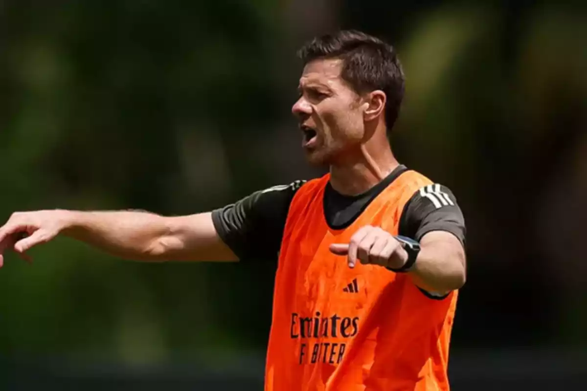 Hombre con chaleco naranja dando indicaciones durante un entrenamiento de fútbol Hombre con chaleco naranja dando indicaciones durante un entrenamiento de fútbol