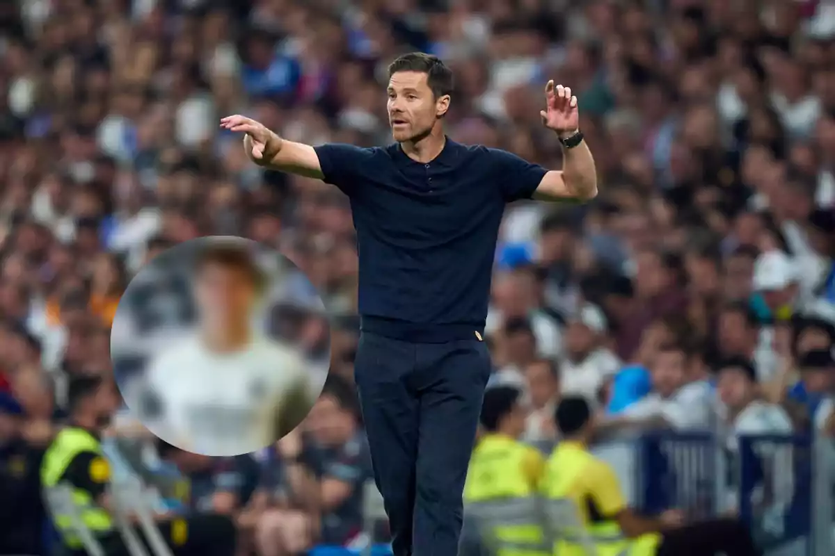 Soccer coach giving instructions on the sideline during a match with the crowd in the background and a blurred figure in the foreground