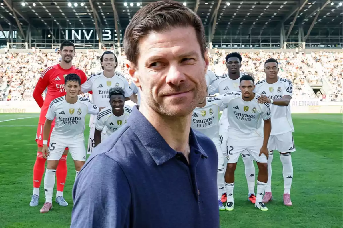 A man in a blue jersey is in front of a group of Real Madrid players posing in a stadium full of spectators.