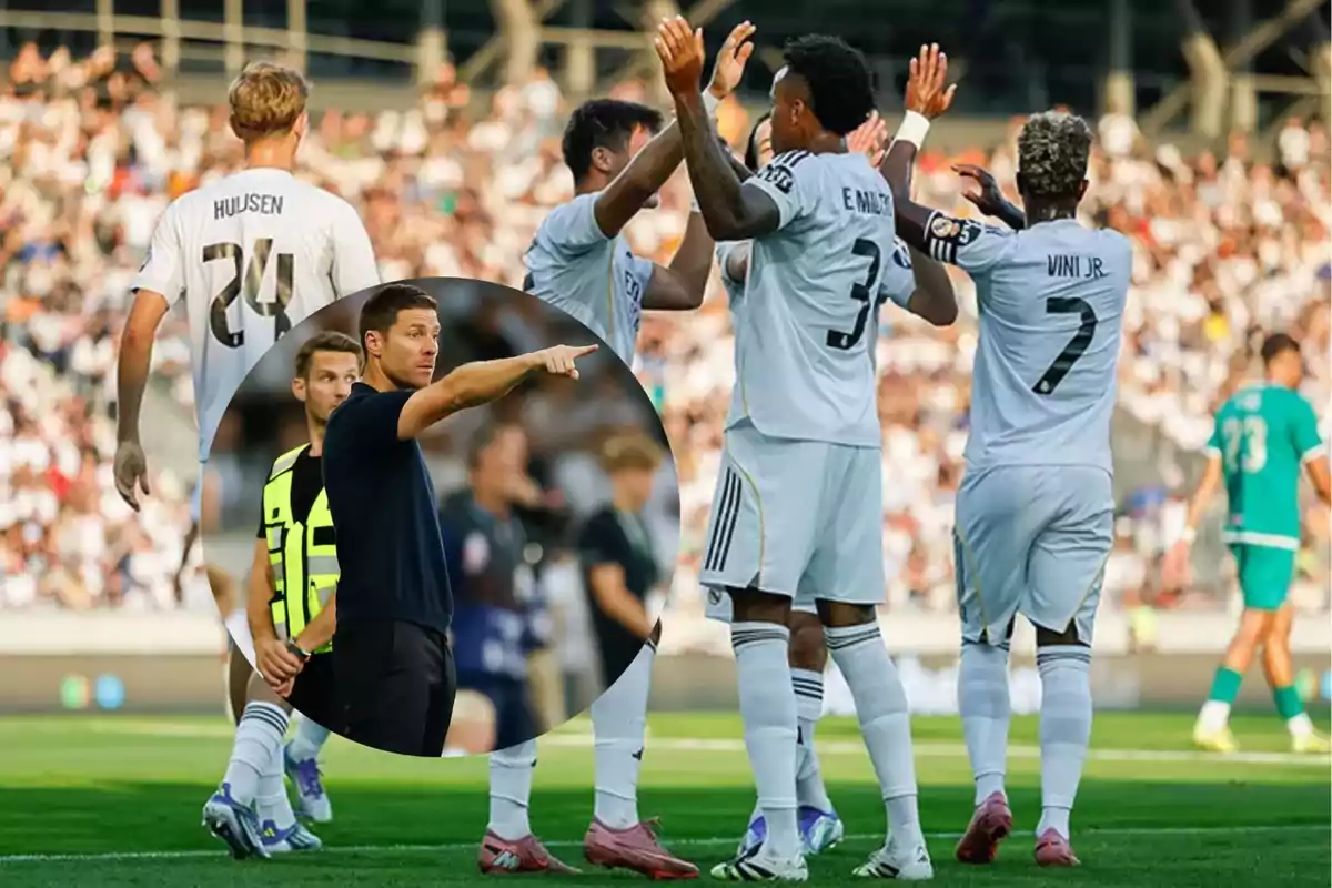 Soccer players celebrate on the field while a coach gives instructions in the foreground.