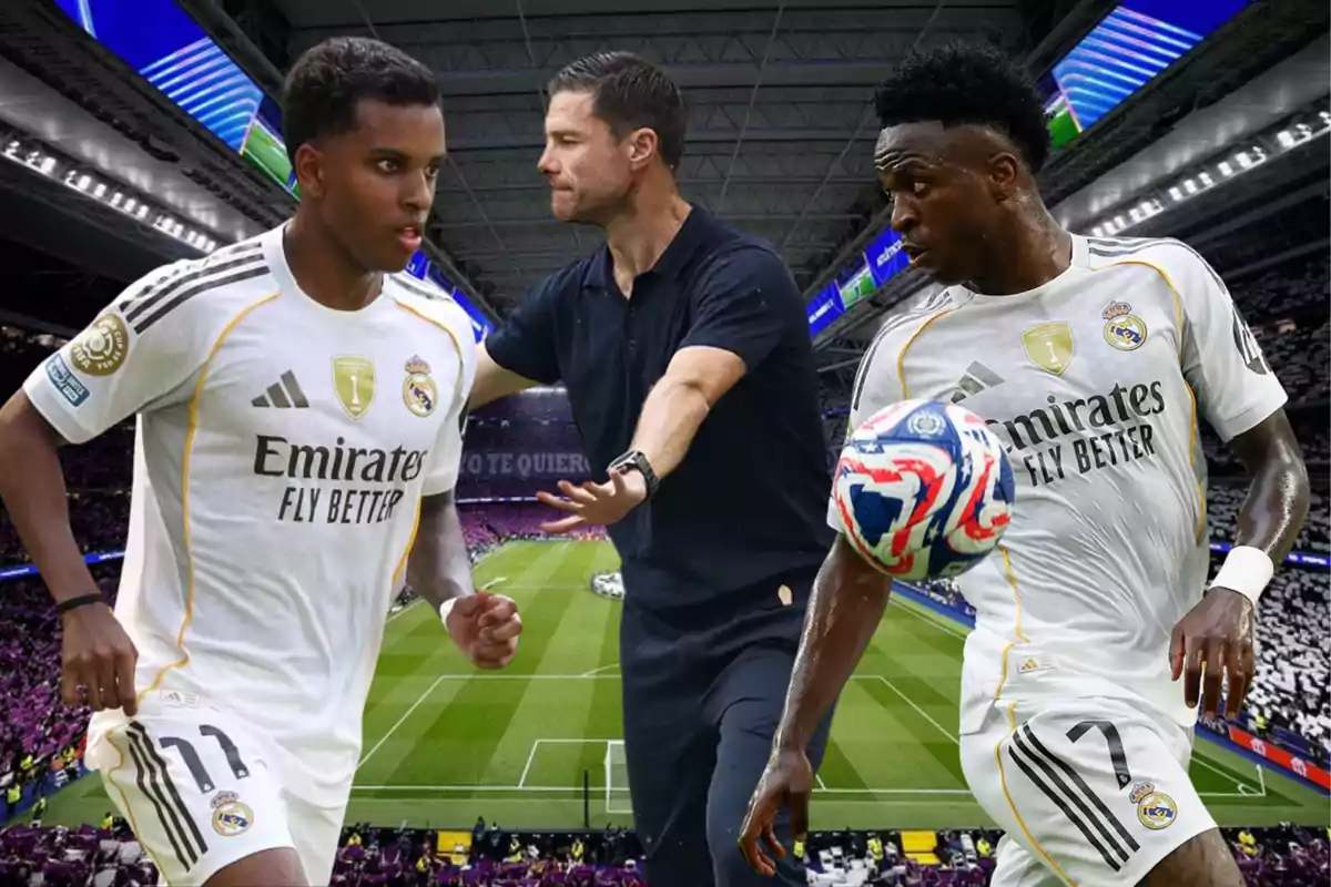 Tres personas en un estadio de fútbol, dos jugadores del Real Madrid con uniforme blanco y un entrenador en el centro dando indicaciones