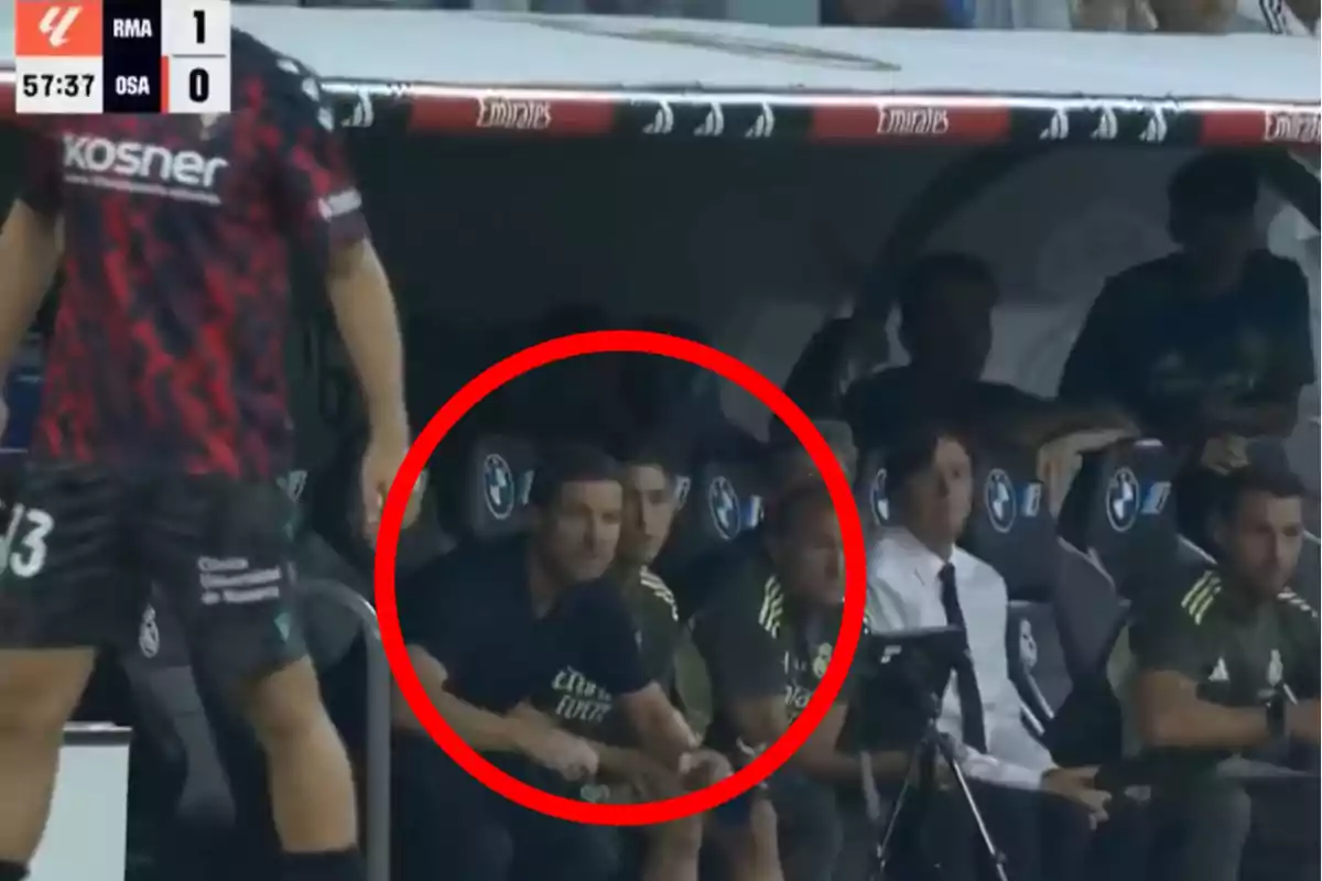A group of people sitting on the bleachers at a soccer stadium during a match, with one of them highlighted by a red circle.