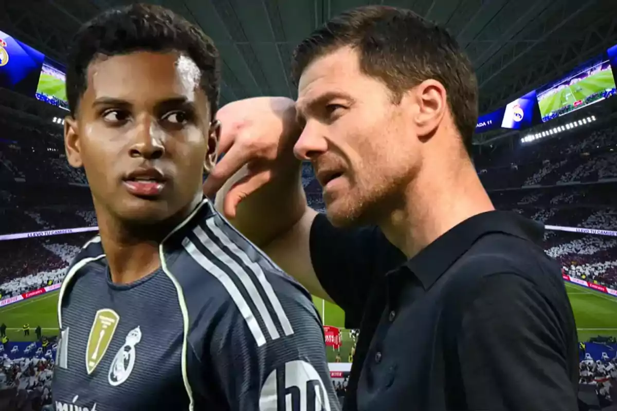Two people in a soccer stadium, one wearing a sports uniform and the other wearing a black t-jersey, seem to be talking during a match.