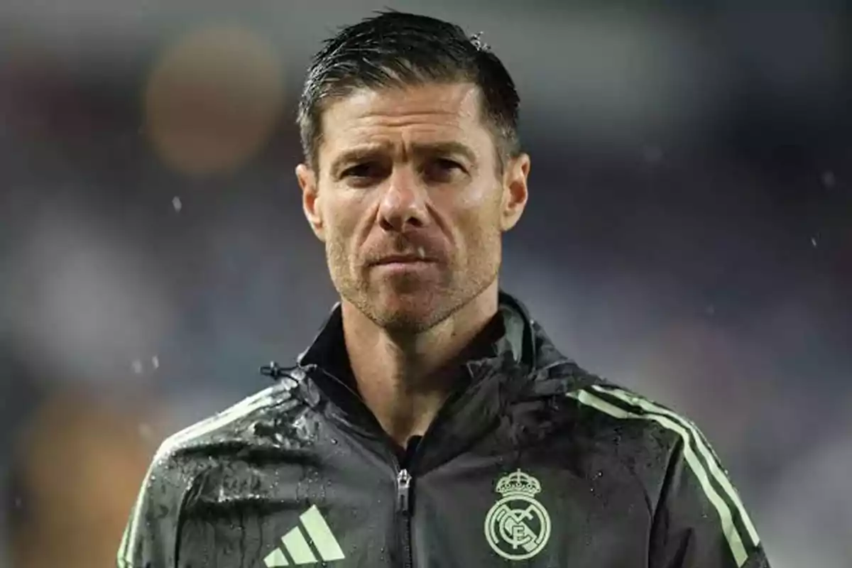 Man wearing a Real Madrid sports jacket standing in the rain looking straight ahead