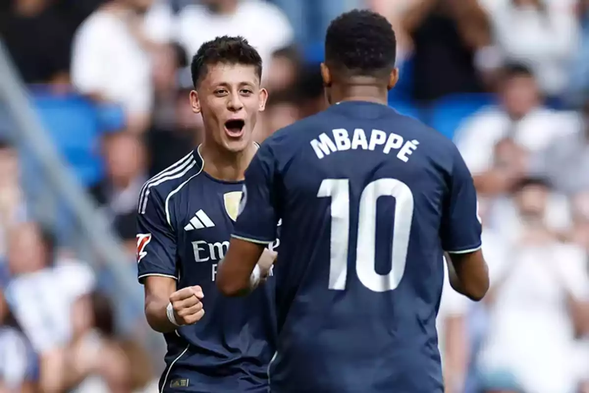 Two players in navy blue uniforms celebrate on the field; one of them wears the number 10 and the name Mbappé on his back. Two players in navy blue uniforms celebrate on the field; one of them wears the number 10 and the name Mbappé on his back.