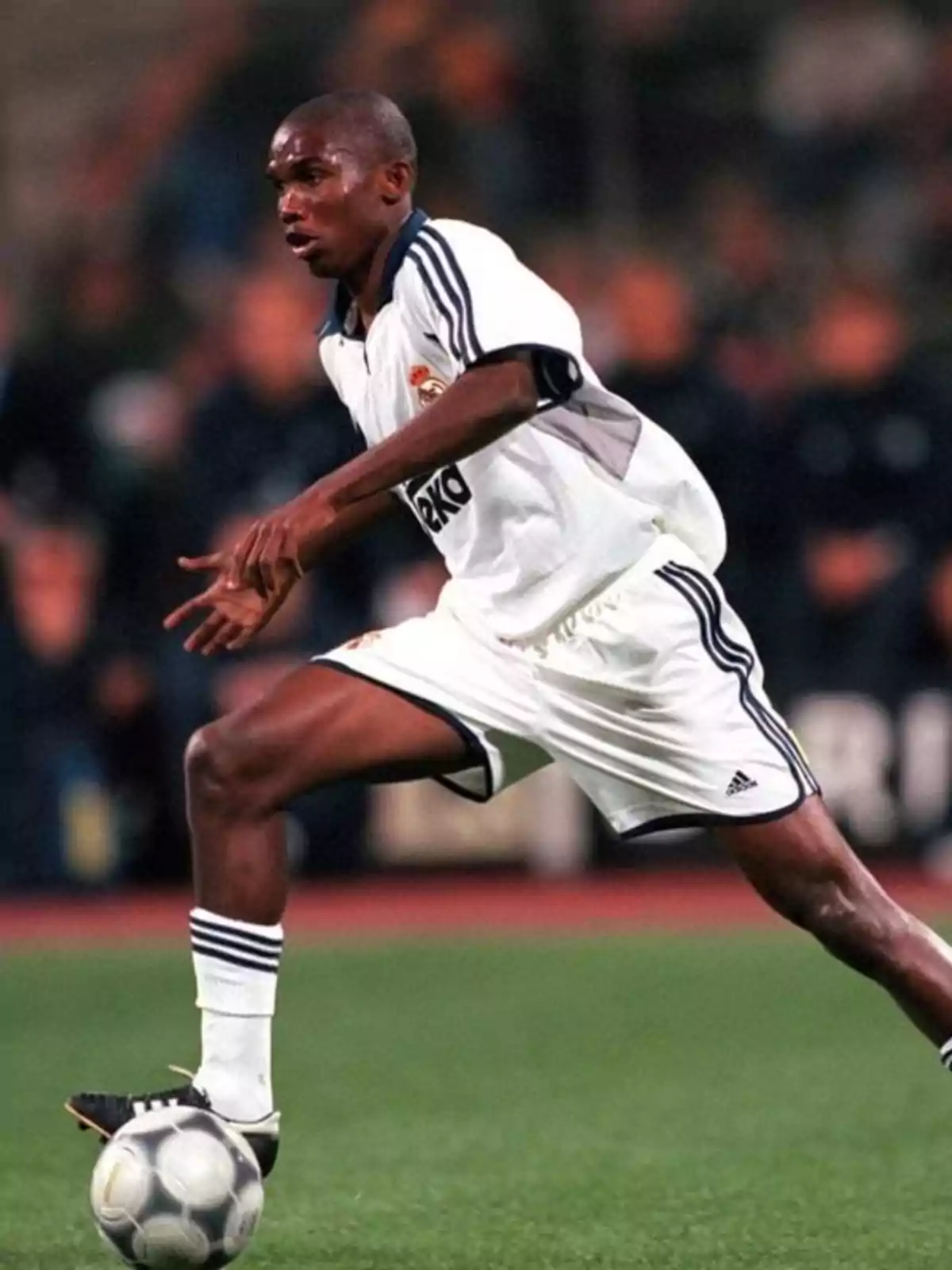 Soccer player in a white Real Madrid uniform controlling the ball during a match Soccer player in a white Real Madrid uniform controlling the ball during a match