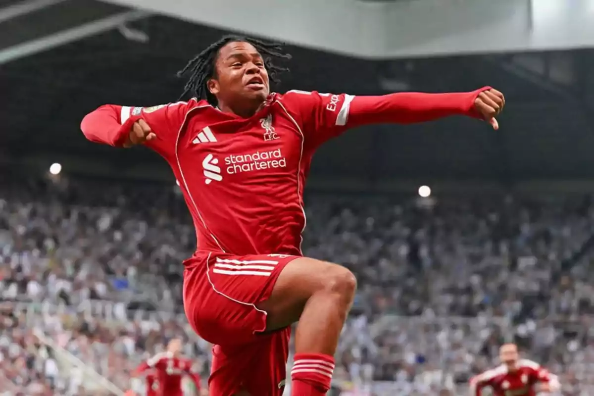 Soccer player in a red uniform celebrating a goal in a stadium full of fans Soccer player in a red uniform celebrating a goal in a stadium full of fans