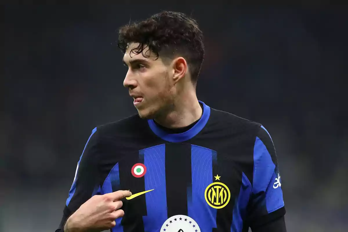 Futbolista con uniforme negro y azul del Inter de Milán señalando el escudo del equipo durante un partido Futbolista con uniforme negro y azul del Inter de Milán señalando el escudo del equipo durante un partido