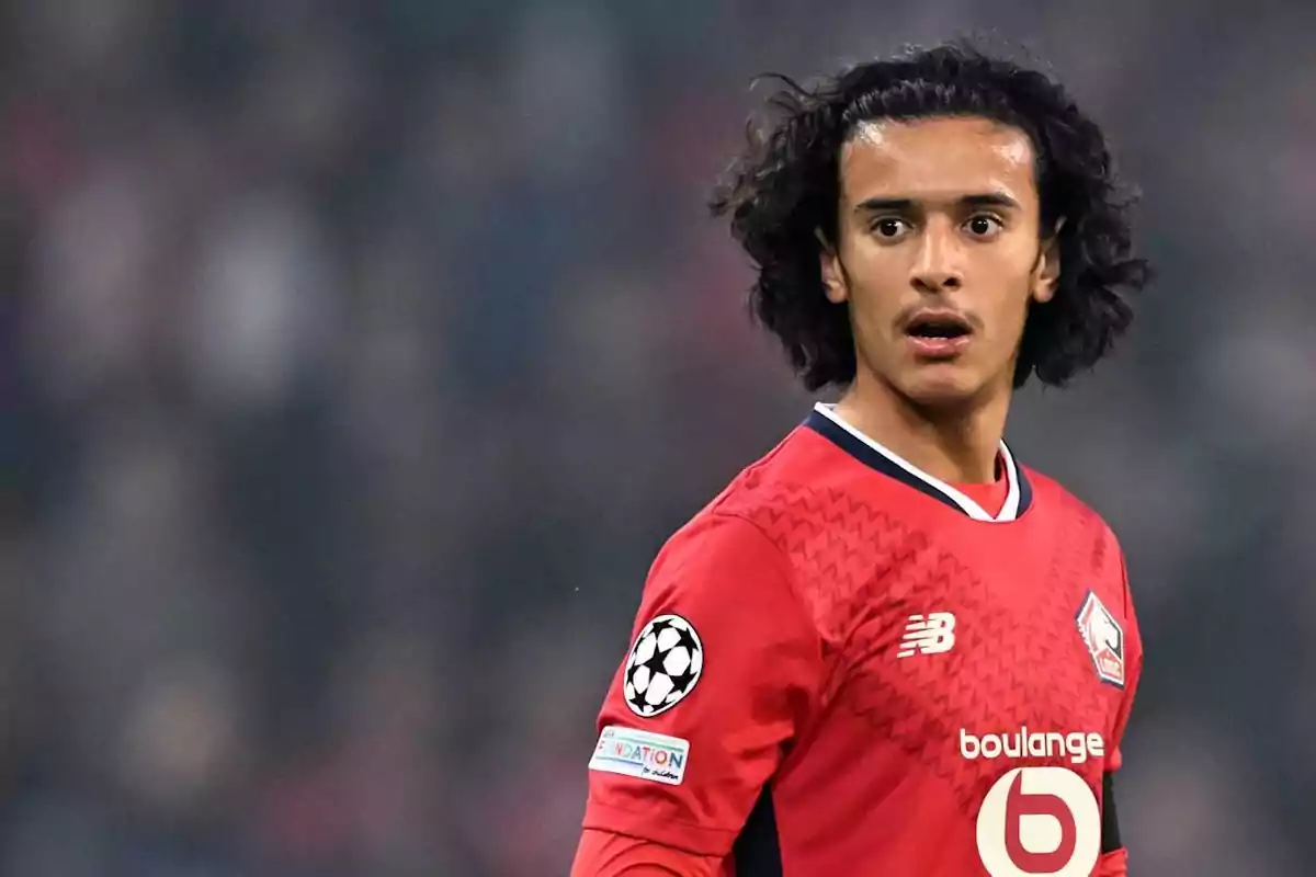 Soccer player with curly hair wearing a red uniform during a match Soccer player with curly hair wearing a red uniform during a match