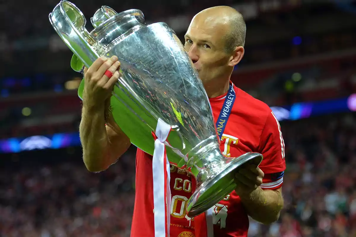 Soccer player kissing the Champions League trophy in a stadium full of fans Soccer player kissing the Champions League trophy in a stadium full of fans