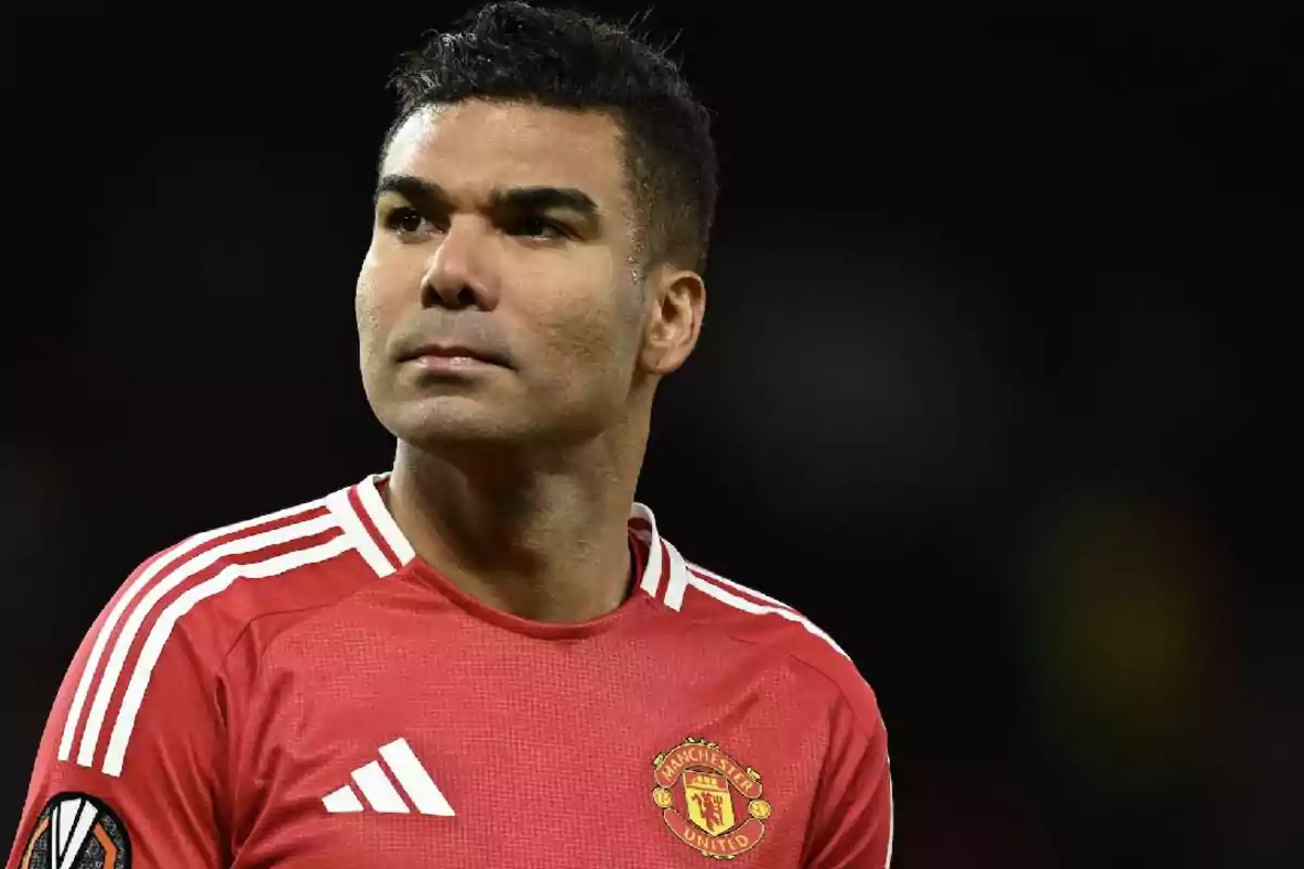 Soccer player wearing a red Manchester United jersey looking to the side in a dark stadium Soccer player wearing a red Manchester United jersey looking to the side in a dark stadium