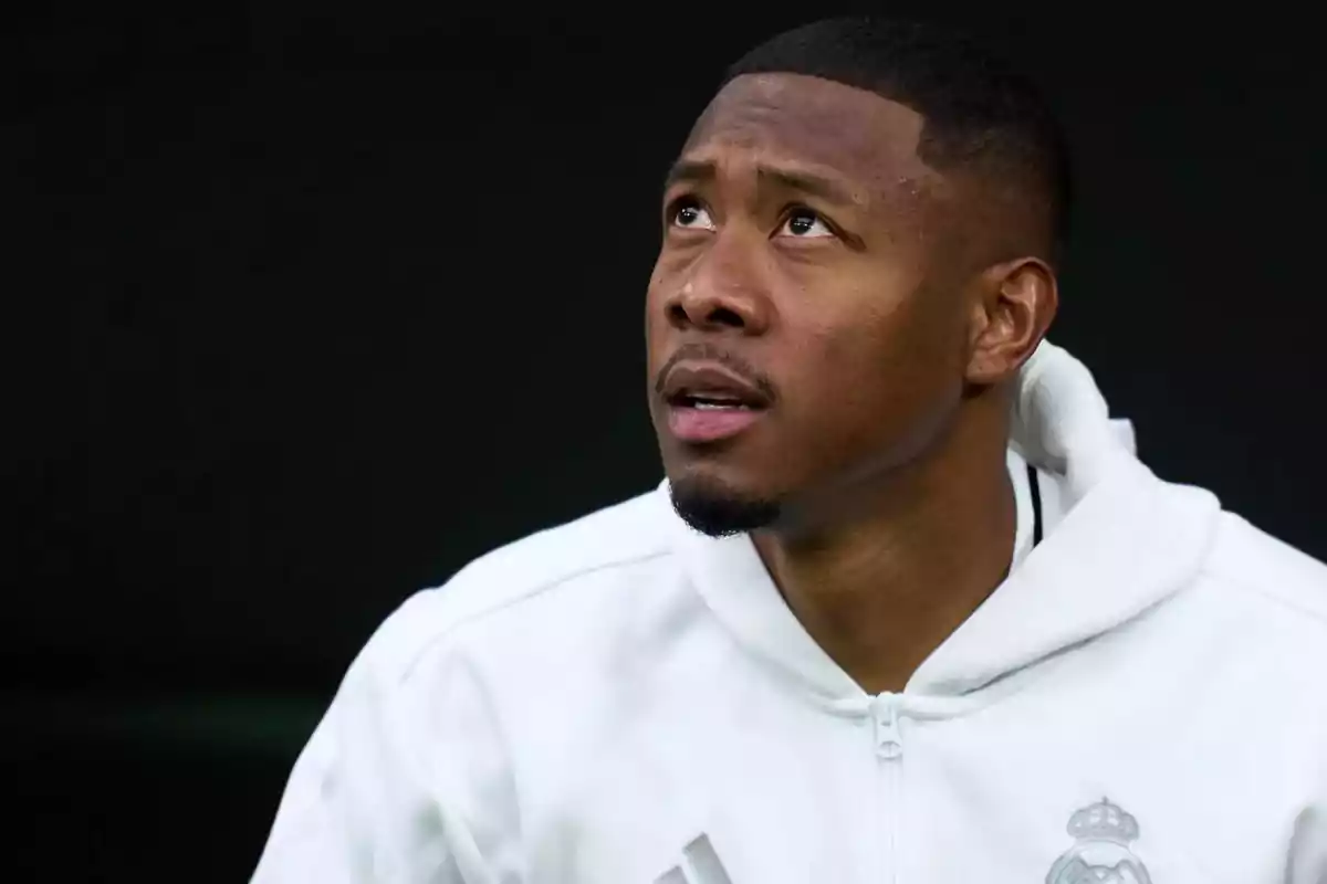 Man in a white Real Madrid jacket looking up with a thoughtful expression Man in a white Real Madrid jacket looking up with a thoughtful expression