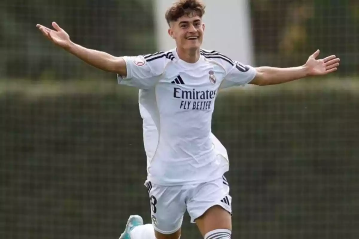 Soccer player in a white uniform celebrating a goal with arms outstretched on a playing field Soccer player in a white uniform celebrating a goal with arms outstretched on a playing field