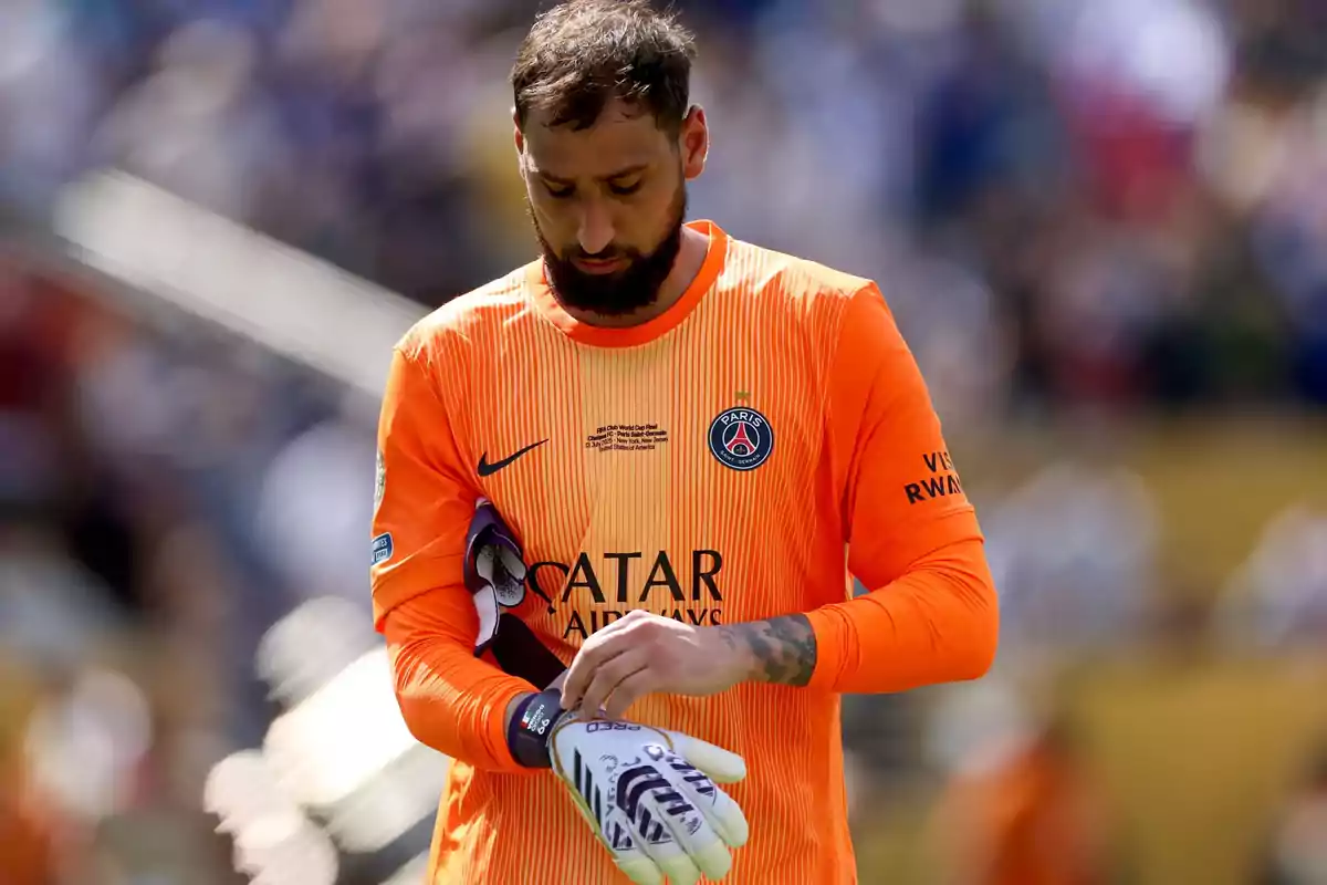 Portero del PSG con uniforme naranja ajustándose los guantes durante un partido Portero del PSG con uniforme naranja ajustándose los guantes durante un partido