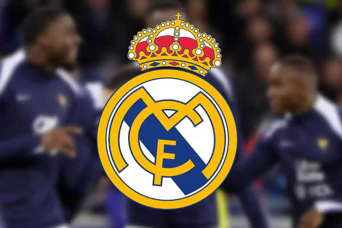 Real Madrid crest in the foreground with blurred players in the background