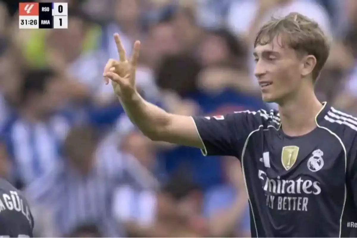 Real Madrid player celebrating on the field, raising two fingers while smiling during a match against Real Sociedad. Real Madrid player celebrating on the field, raising two fingers while smiling during a match against Real Sociedad.