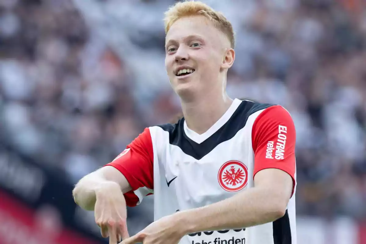 Soccer player in a white and red Eintracht Frankfurt uniform celebrating on the field Soccer player in a white and red Eintracht Frankfurt uniform celebrating on the field