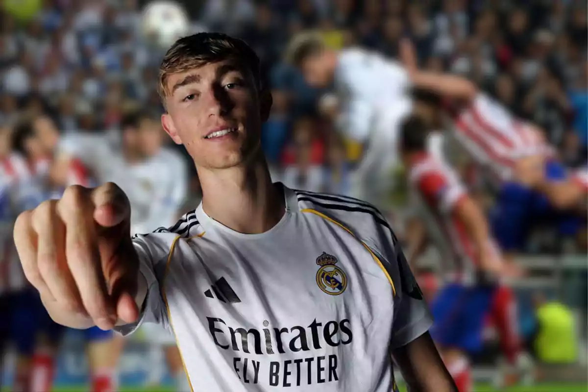 Jugador del Real Madrid señalando hacia la cámara con fondo de partido de fútbol desenfocado