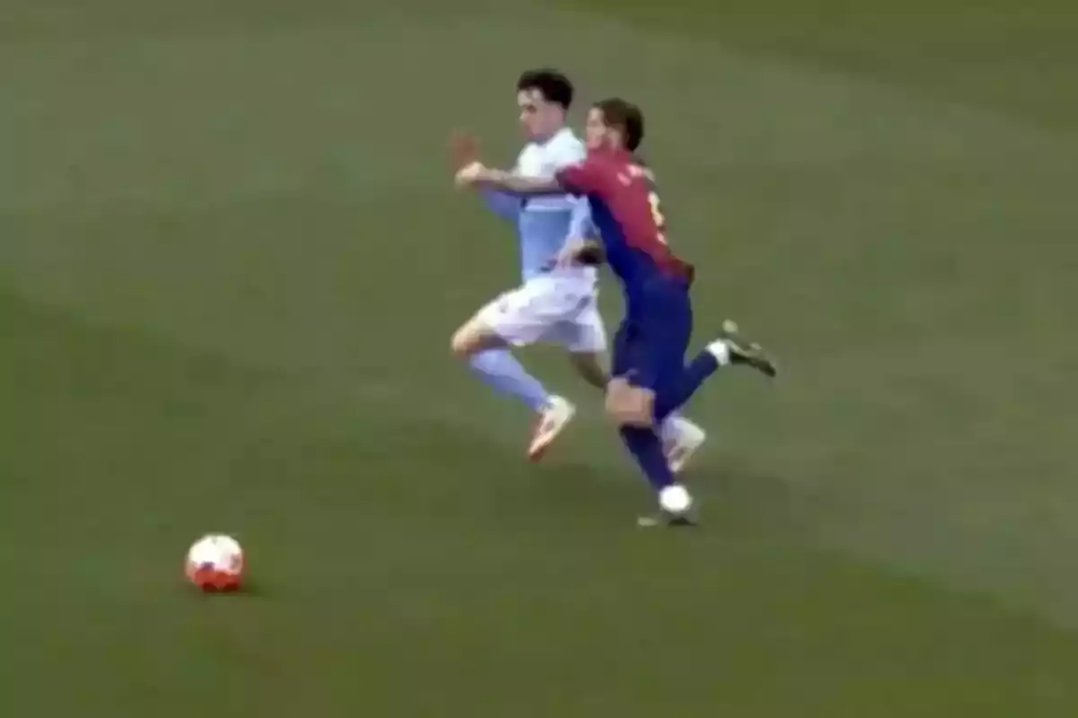 Dos futbolistas disputan el balón mientras uno de ellos comete una falta sujetando al rival en pleno partido. Dos futbolistas disputan el balón mientras uno de ellos comete una falta sujetando al rival en pleno partido.
